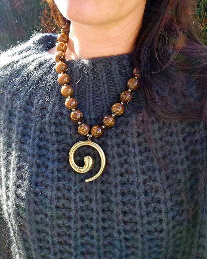 collier perles marron pendentif spirale doré porté sur un pull