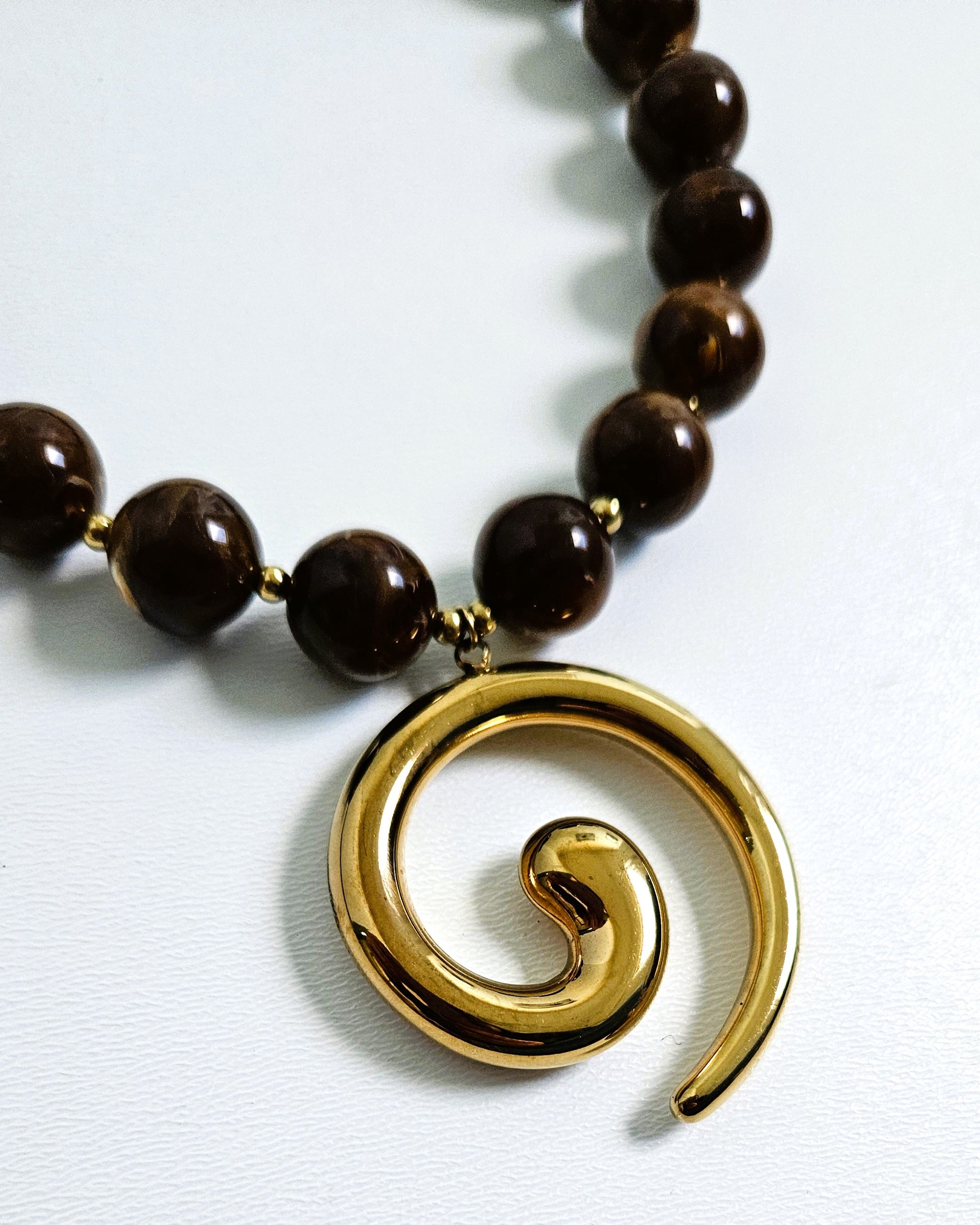 pendentif spirale courbes doré gros plan